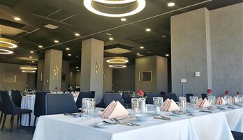 Un salón de conferencias con mesas redondas, sillas e iluminación moderna.