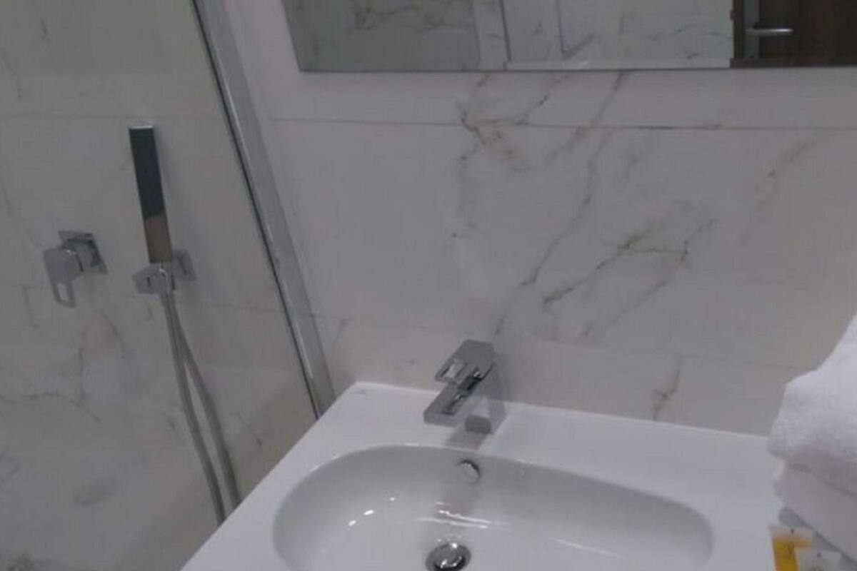 Een badkamer met een witte wasbak, een spiegel erboven en een handdoek aan de rechterkant.