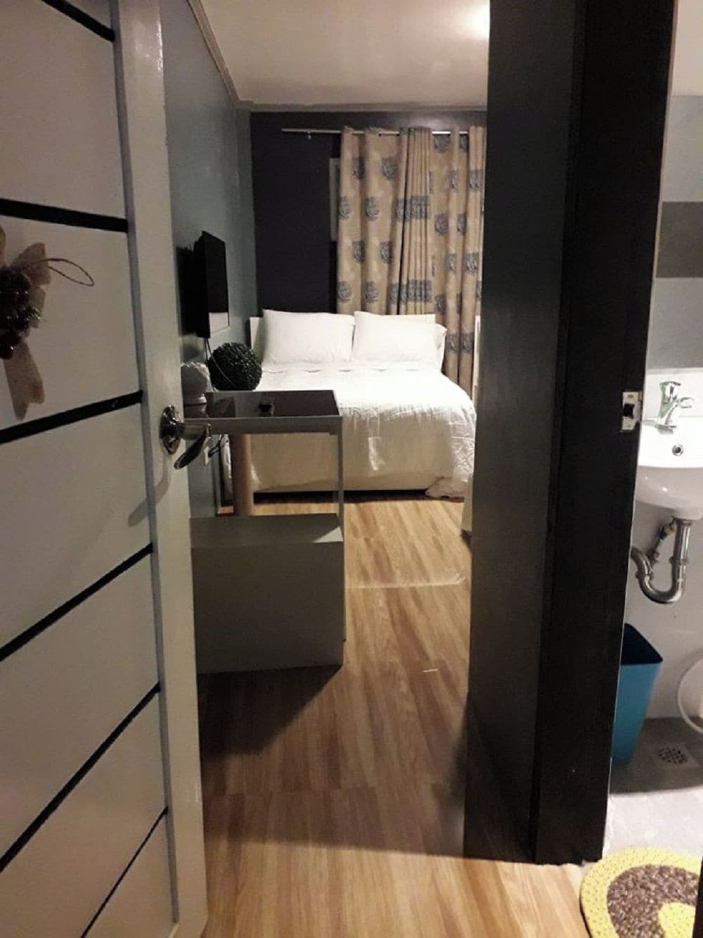 Et hotelværelse med seng, natbord, spejl og badeværelse med vask og toilet.