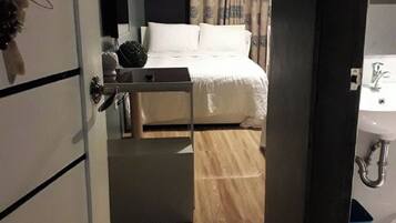 Et hotelværelse med seng, natbord, spejl og badeværelse med vask og toilet.