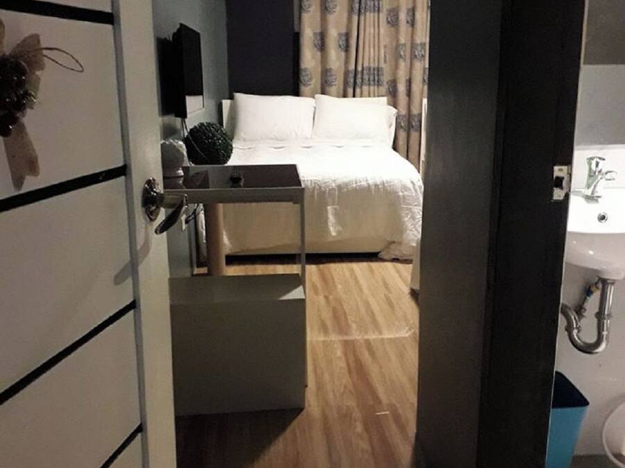Et hotelværelse med seng, natbord, spejl og badeværelse med vask og toilet.