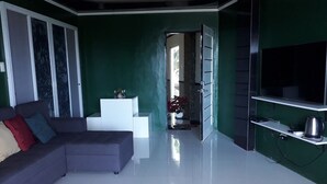 A modern living room with a grey sofa, a white coffee table, and a green accent wall.