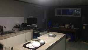 A compact kitchen with a sink, stove, and various appliances. There is a window with a view of the outside.