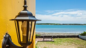 A yellow wall with a black outdoor lamp and a view of a beach and ocean. - Summer Ya B&B (Huxi)