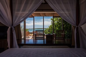 A bedroom with a large window overlooking a balcony with wooden furniture and a view of the sea. - Summer Ya B&B (Huxi)