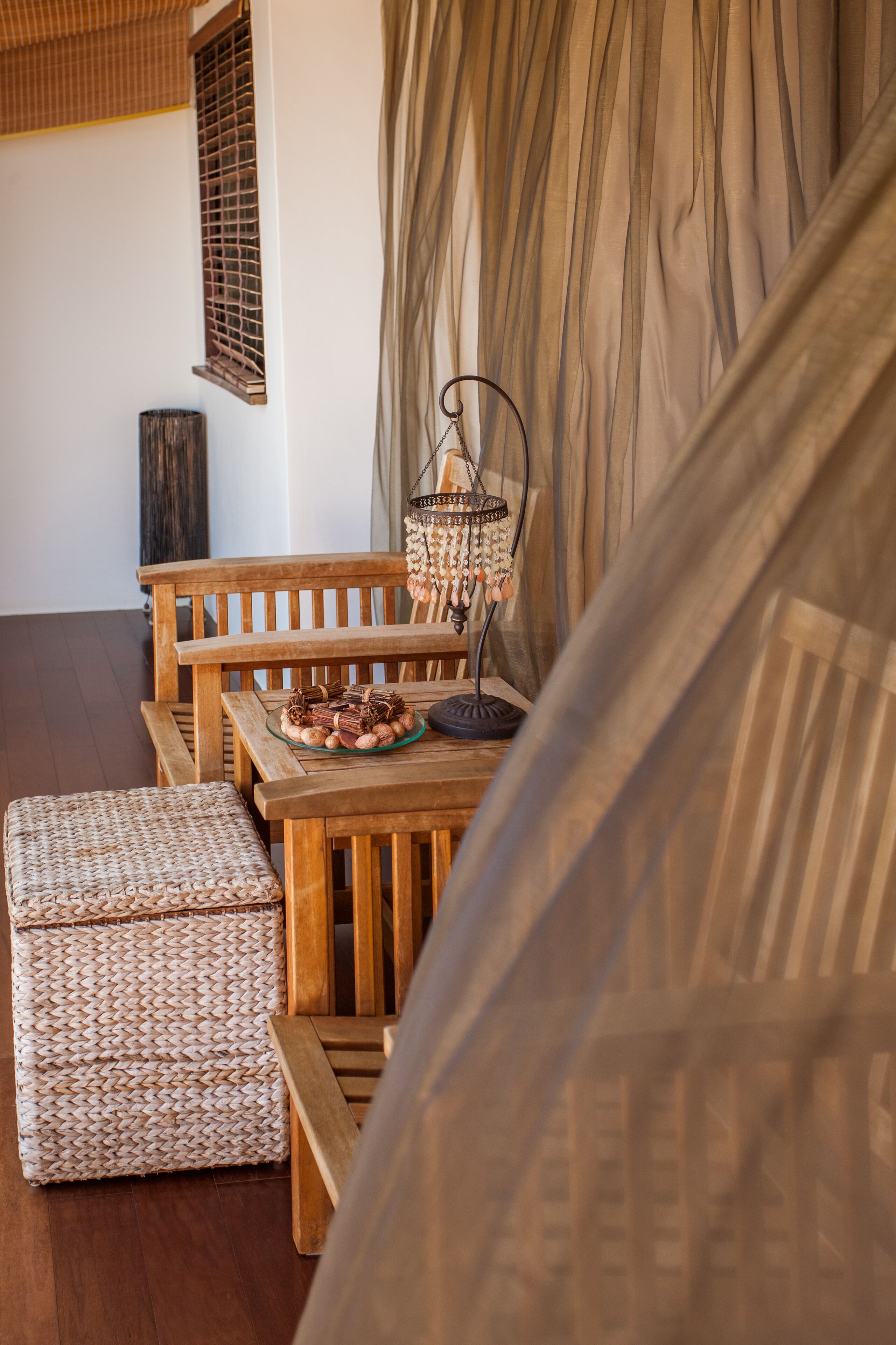 A wooden dining table with a woven bench and a wicker ottoman.