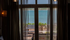 A room with a large window overlooking a body of water, a wooden deck outside, and a lamp on the left. - Summer Ya B&B (Huxi)