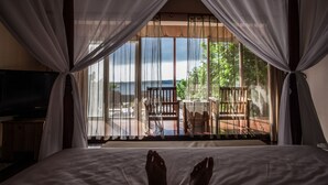 A bedroom with a bed, a TV, and a view of the outdoors through sheer curtains. - Summer Ya B&B (Huxi)