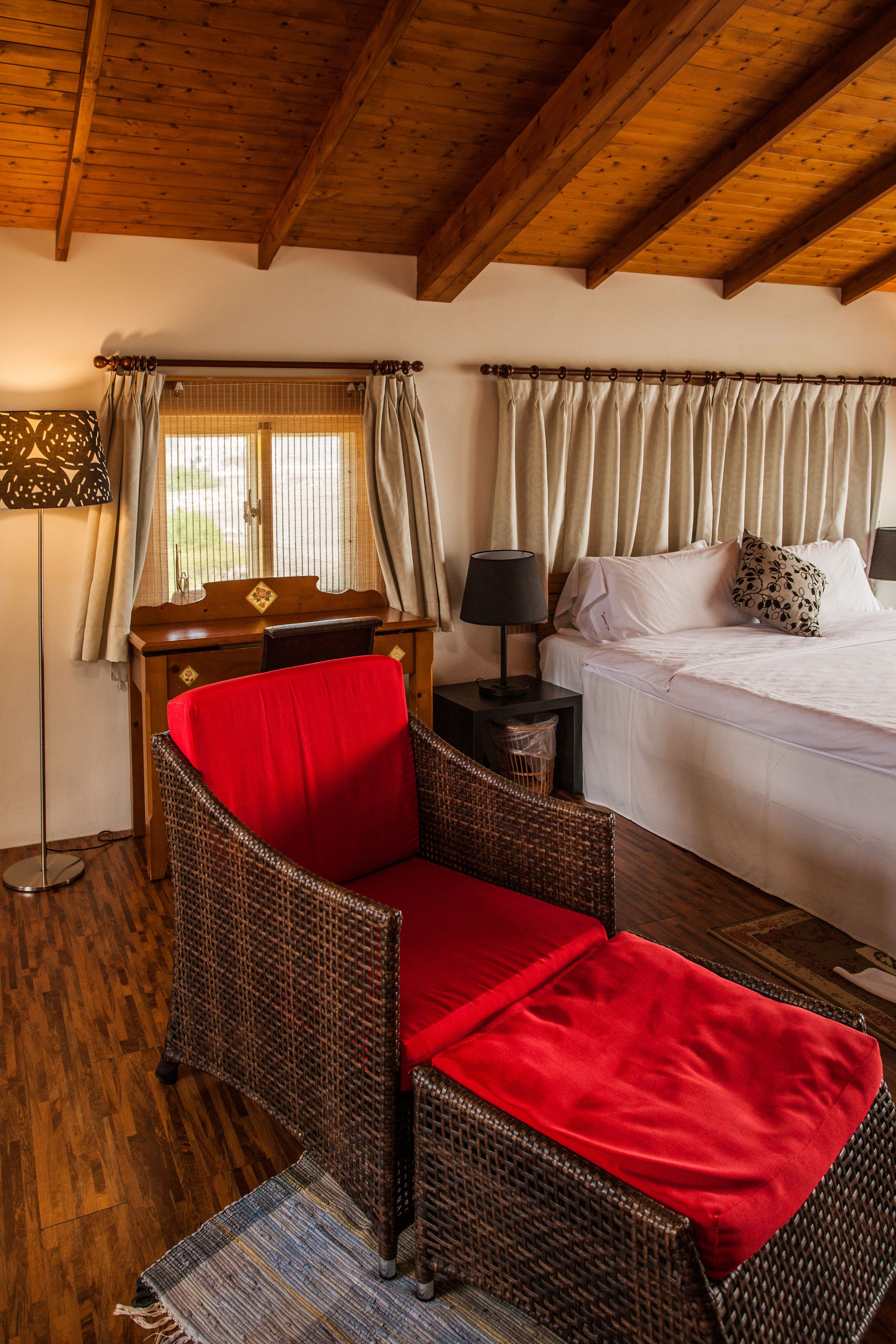 A room with a bed, a desk, a chair, and a floor lamp.