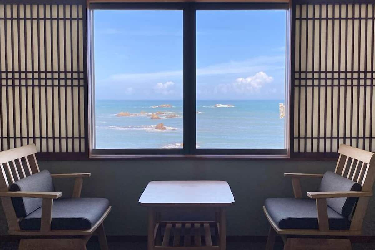 A room with a large window, two chairs, and a small table.
