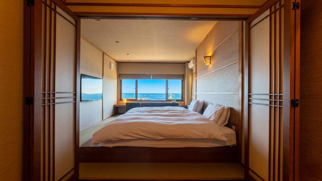 Une chambre avec un lit, une vue sur la mer et des portes coulissantes.