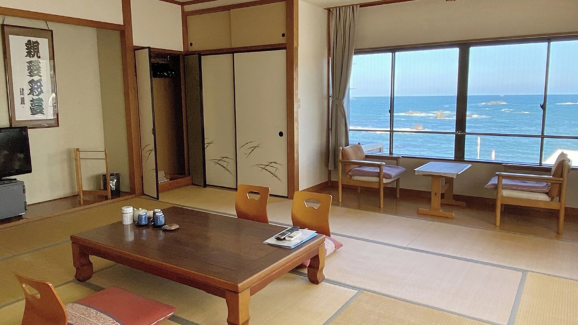 Habitació japonesa tradicional amb sòl de tatami, una taula baixa i vista a l'oceà.