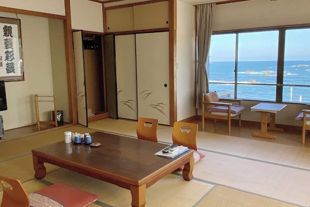 A traditional Japanese room with tatami flooring, a low table, and a view of the ocean.