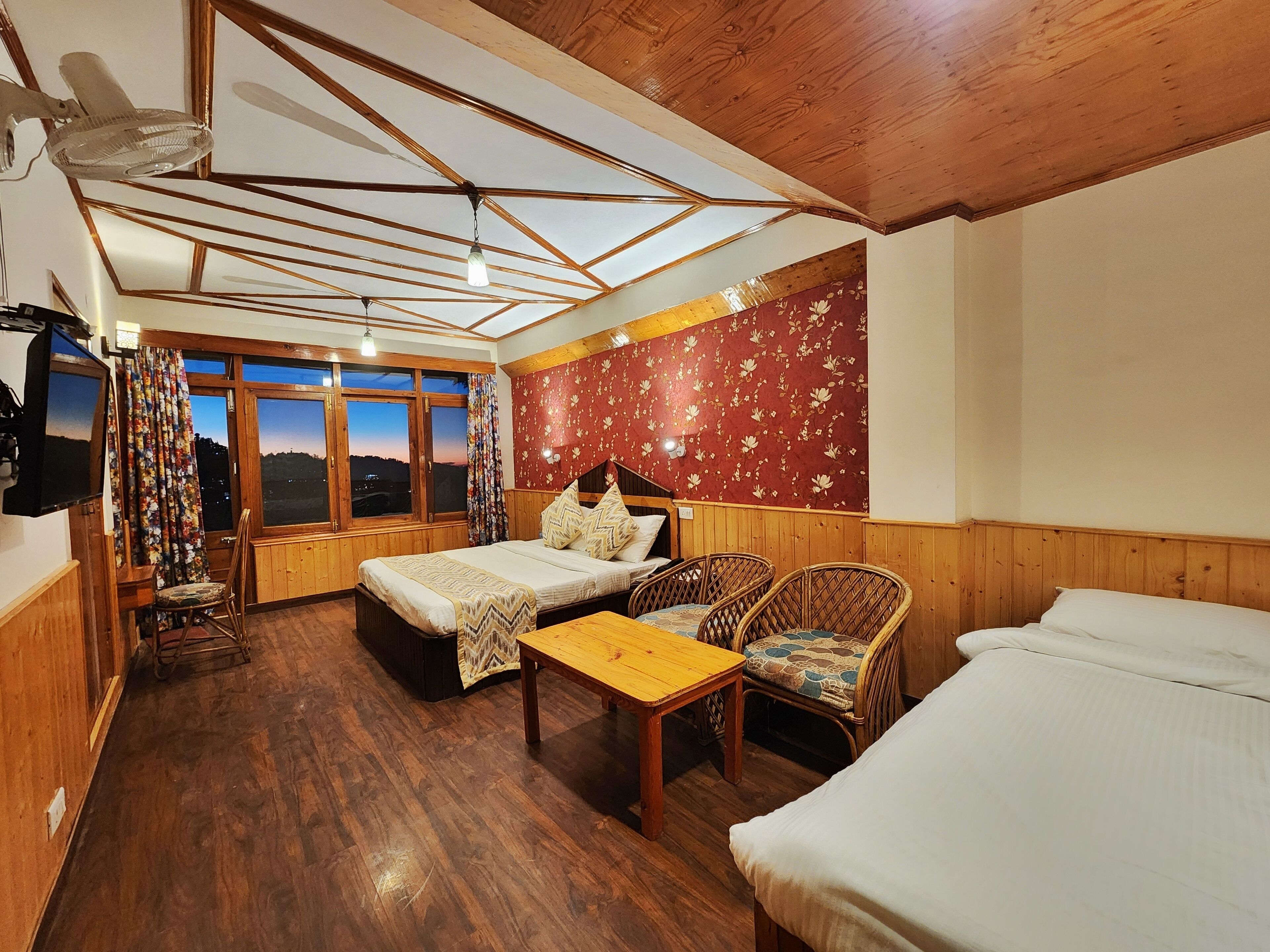Quarto com teto de madeira, cama, sofá, mesa e televisão.