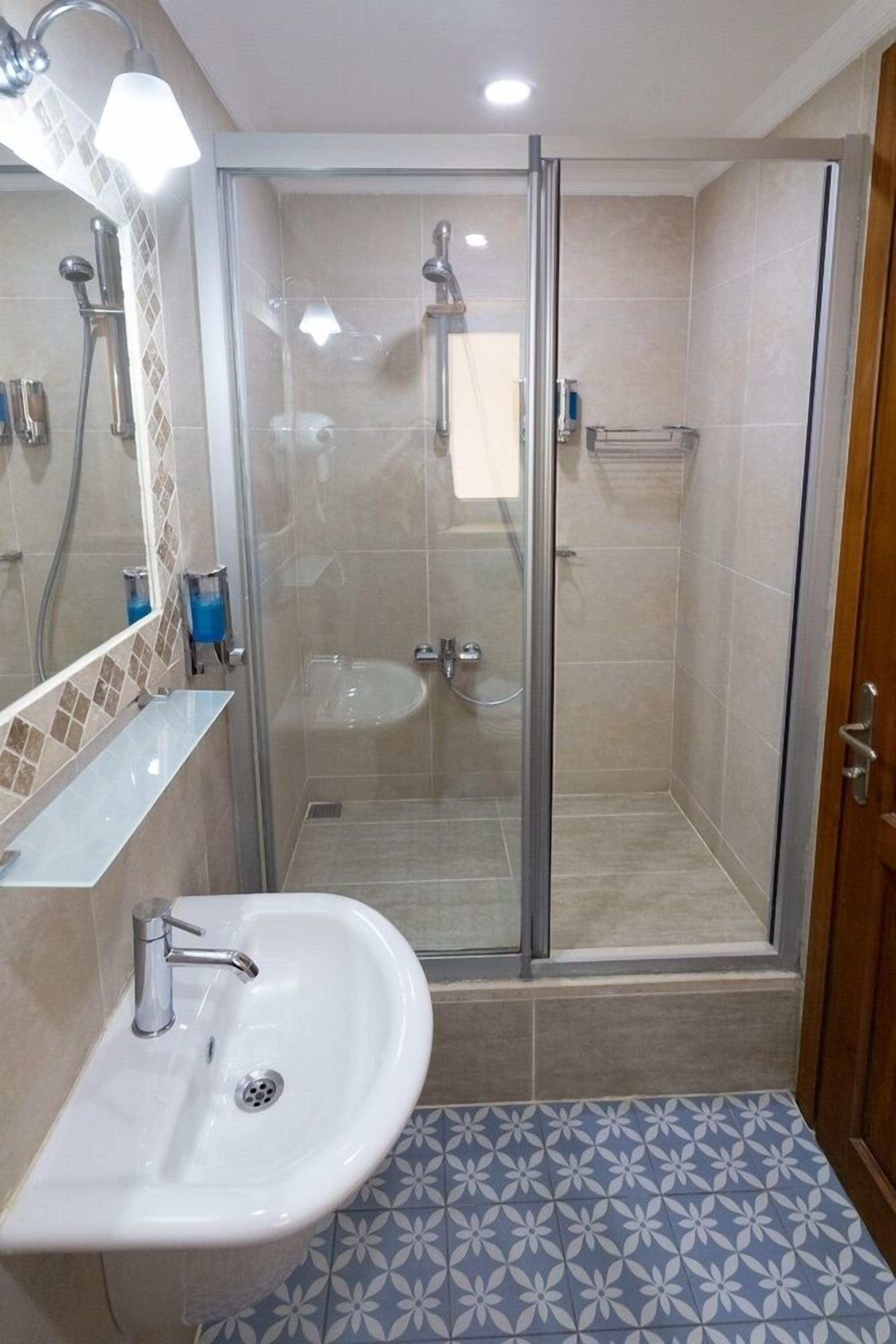 Un baño con ducha envuelta en vidrio, un lavabo y un espejo.