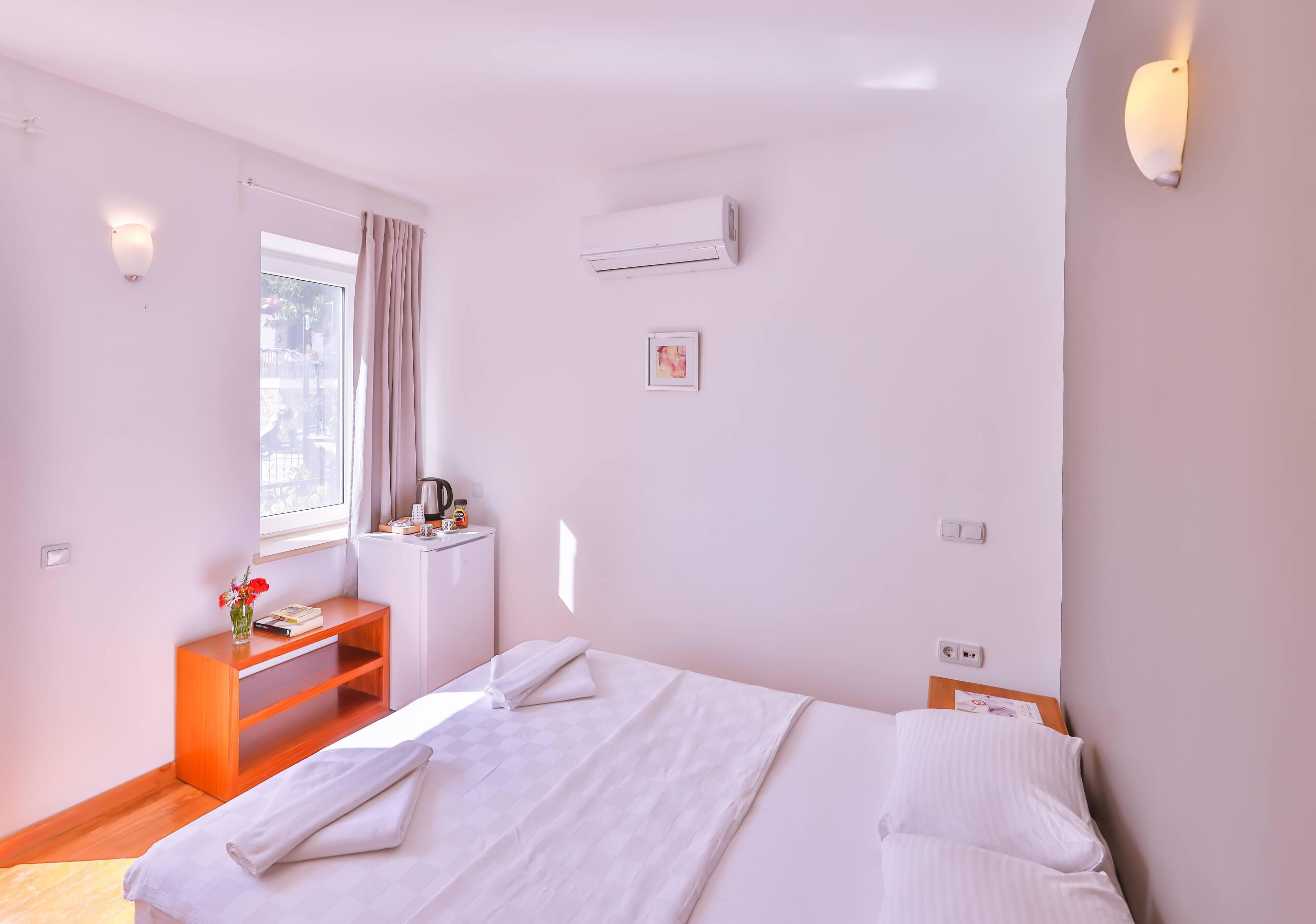 A neatly arranged bedroom with a bed, bedside table, and a window with curtains.