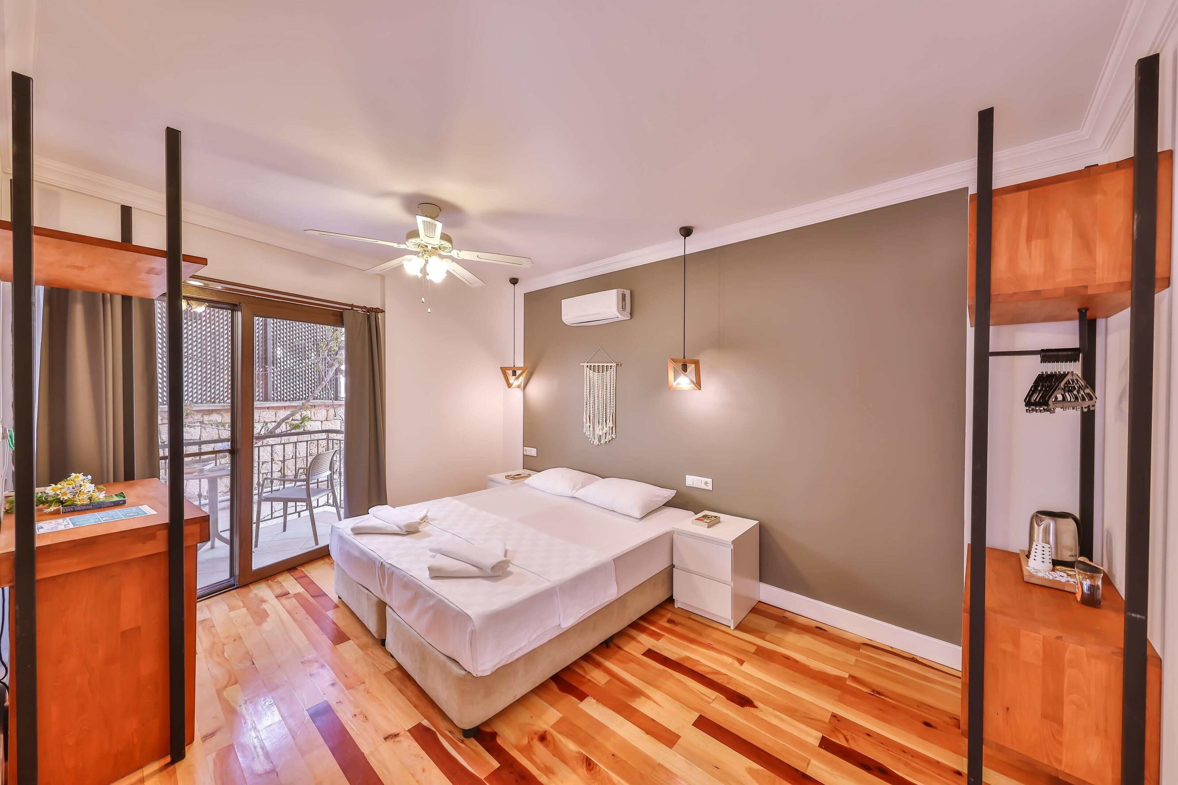 Une chambre à coucher avec un lit, des tables de chevet, un ventilateur de plafond et un balcon avec vue.