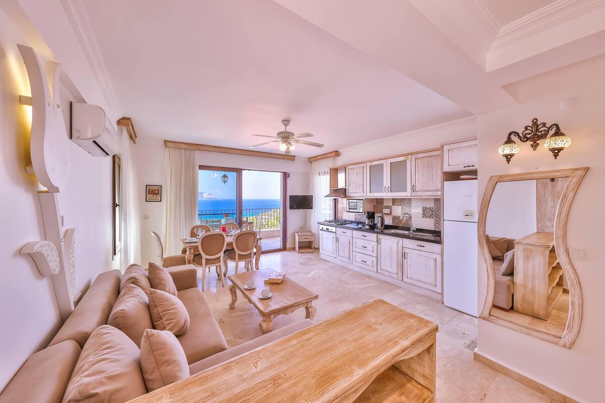 A spacious living area with a sofa, coffee table, and a view of the sea through large windows.