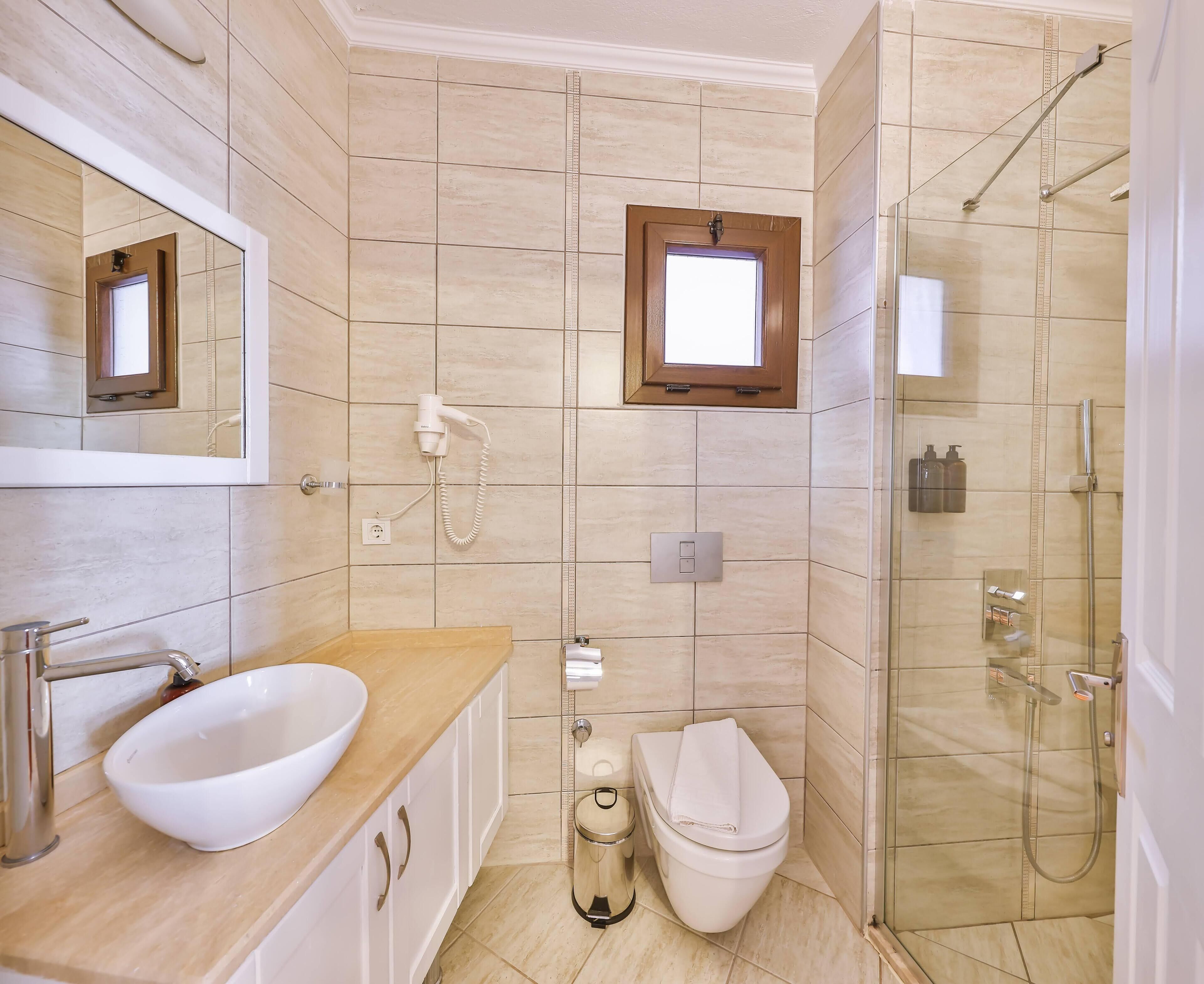 Un baño moderno con lavamanos, espejo, inodoro y ducha.