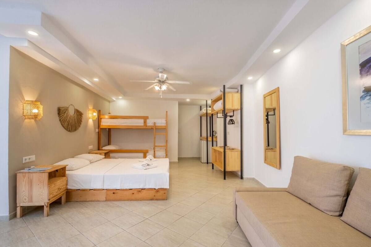 A bedroom with a bunk bed, bedside table, and a sofa.