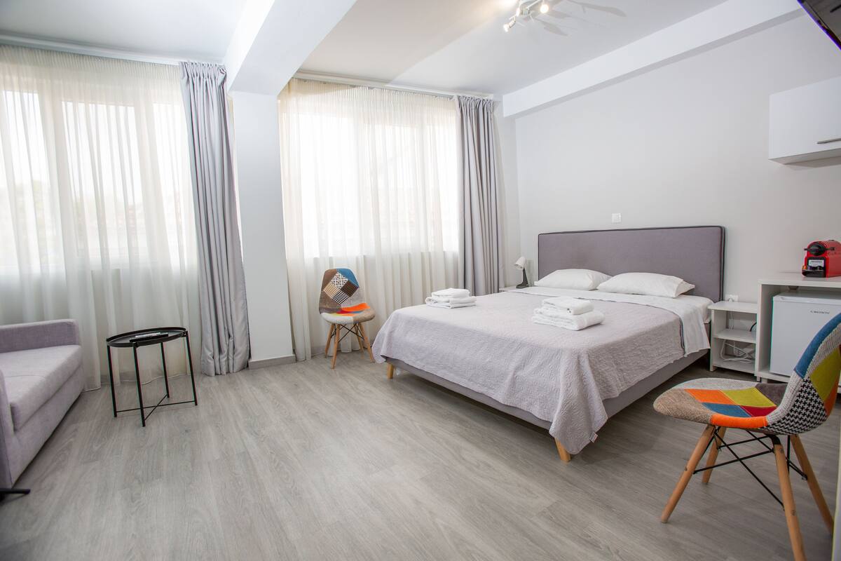 A modern hotel room with a bed, a chair, a small table, and a sofa.