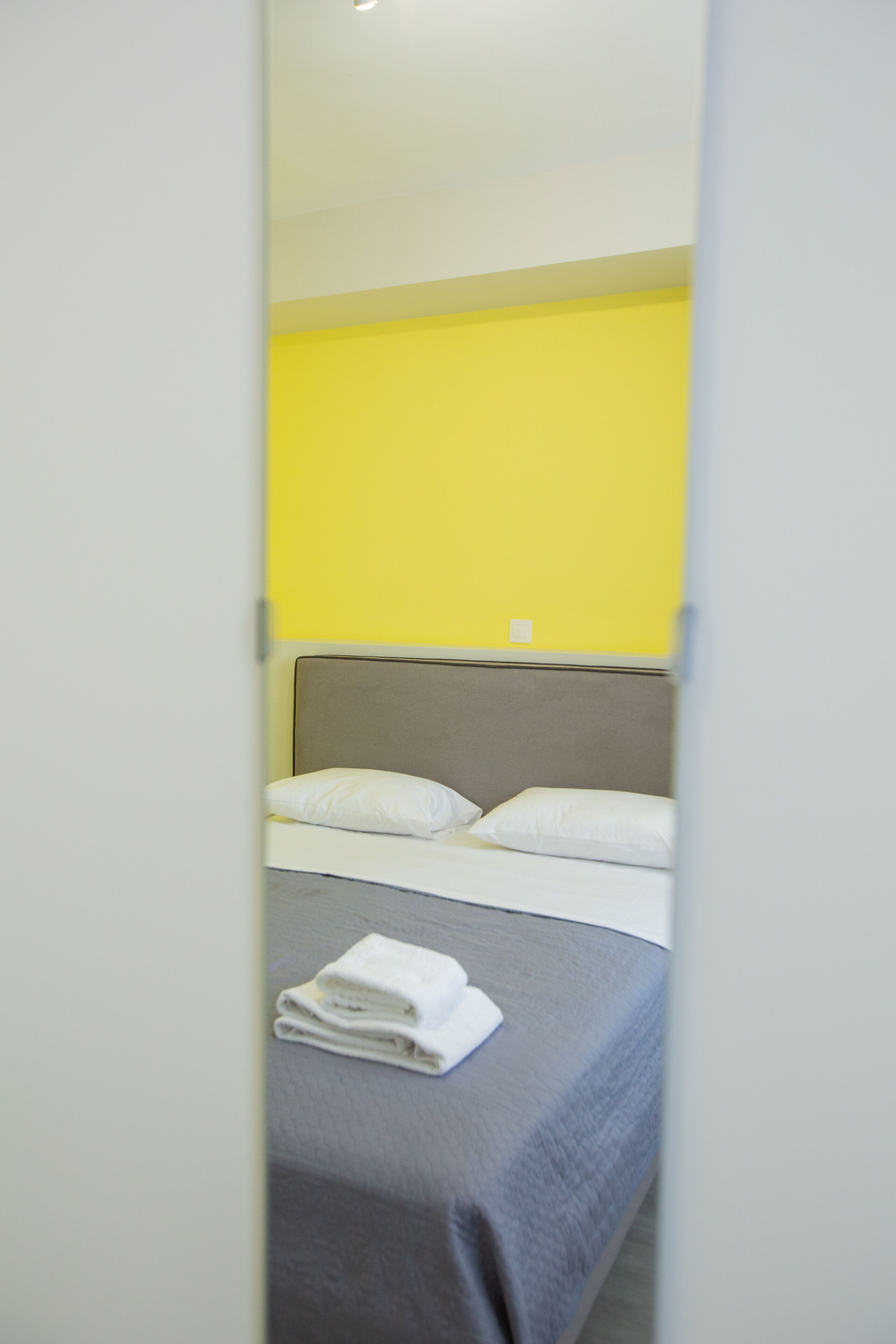 Ein Hotelzimmer mit einem Bett, Kissen und einem gefalteten Handtuch.