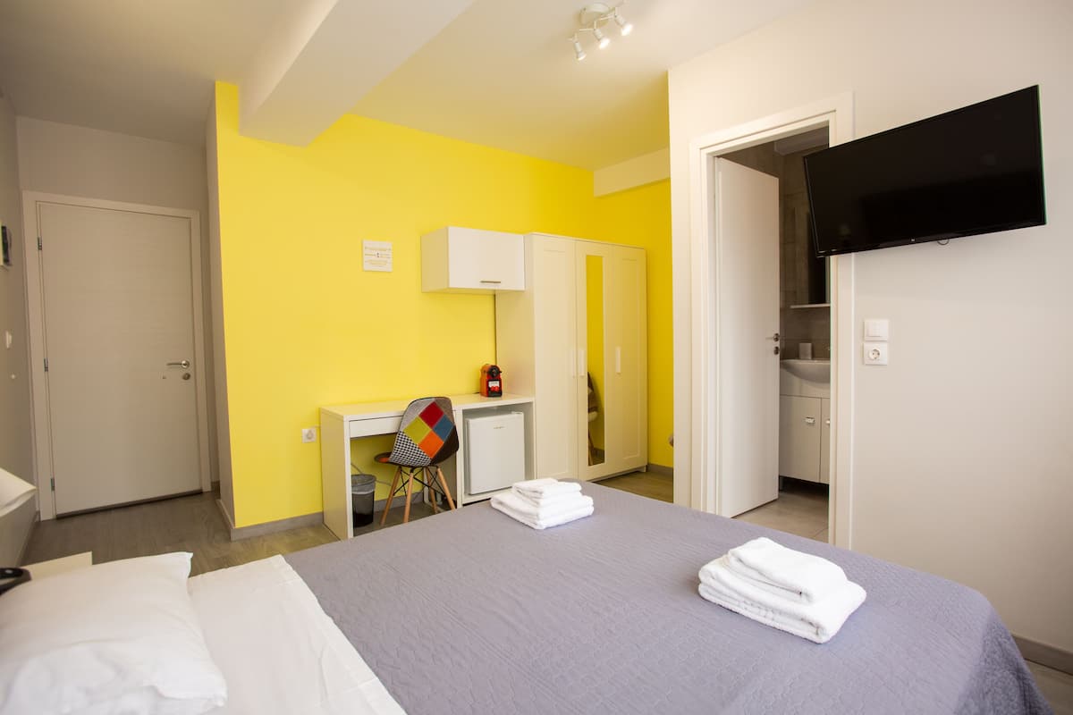 A hotel room with a bed, a desk, a chair, and a TV.