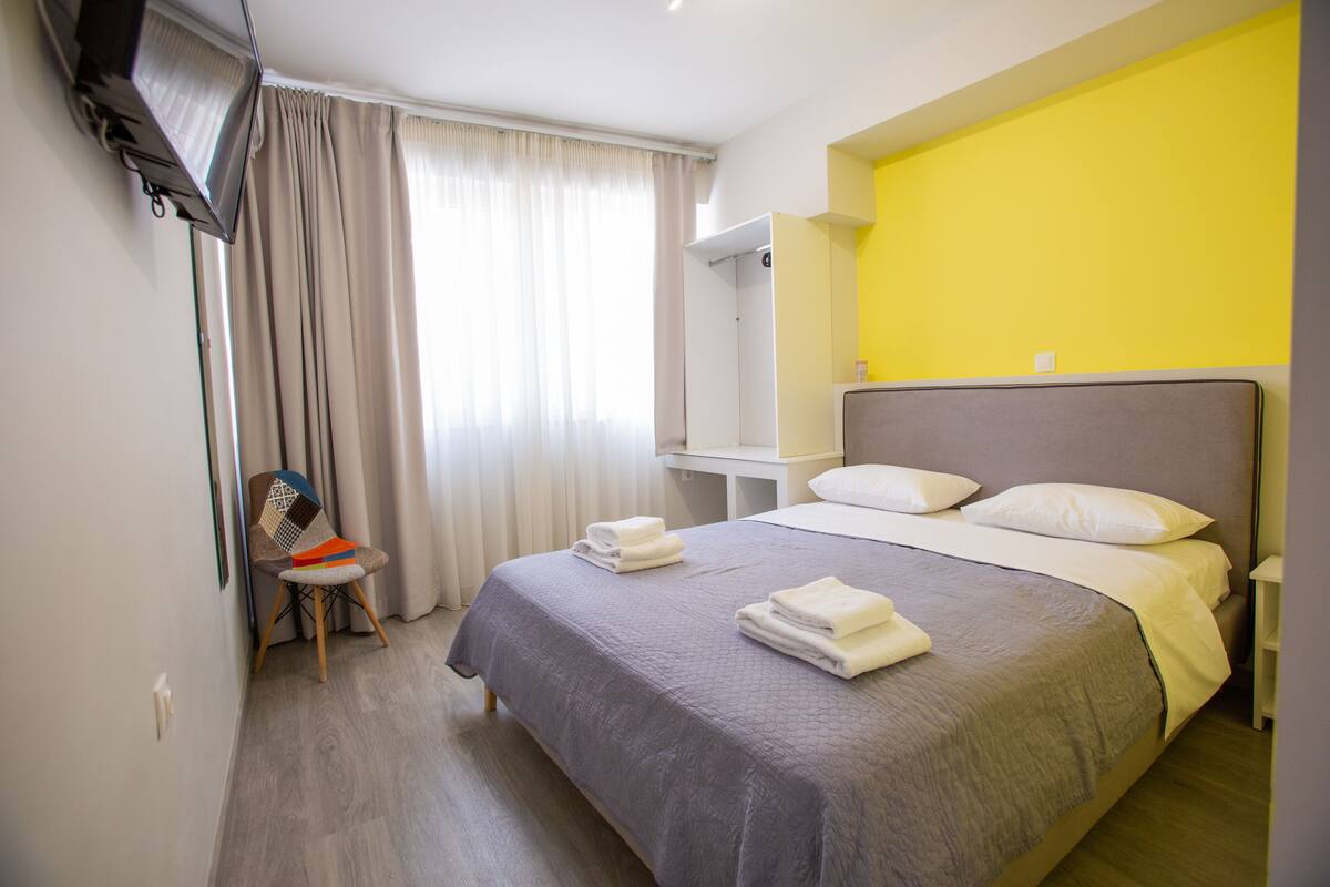 A hotel room with a bed, a chair, a desk, and a television.