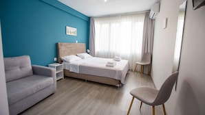 A modern hotel room with a bed, a sofa, a chair, and a window with curtains. - Raise Rooms in Center of Athens (Athens)