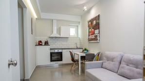 A compact living space with a kitchenette, a dining area with a table and chairs, and a sofa. - Raise Rooms in Center of Athens (Athens)