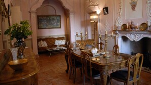 A dining room with a table set for four, surrounded by ornate chairs. A chandelier hangs above the table, and a painting is visible on the wall. - Palazzo Bonfranceschi (Belforte del Chienti)