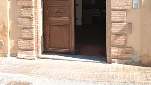 A wooden door with a brick archway, leading into a building. - Palazzo Bonfranceschi (Belforte del Chienti)
