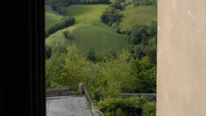 A view from a window overlooking rolling green hills and a cloudy sky. - Palazzo Bonfranceschi (Belforte del Chienti)