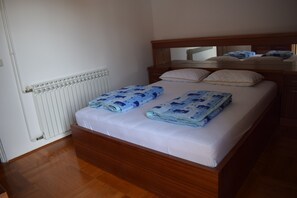 Ein Schlafzimmer mit einem hölzernen Bett, weißer Bettwäsche, einem Heizkörper und einem Spiegel über dem Bett.