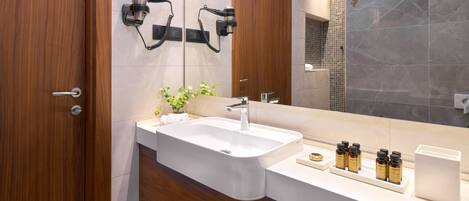 A modern bathroom with a large sink, wooden vanity, and a mirror.