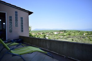 Un balcón con sillones de sol con vistas a un paisaje pintoresco.