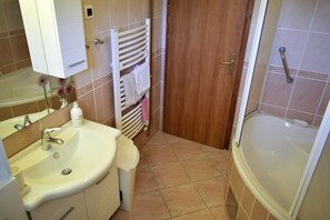 A bathroom with a sink, mirror, towel rack, and bathtub. - Apartment Lucy (Krk)