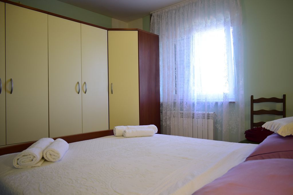 A hotel room with a large bed, a wardrobe, and a window with curtains.