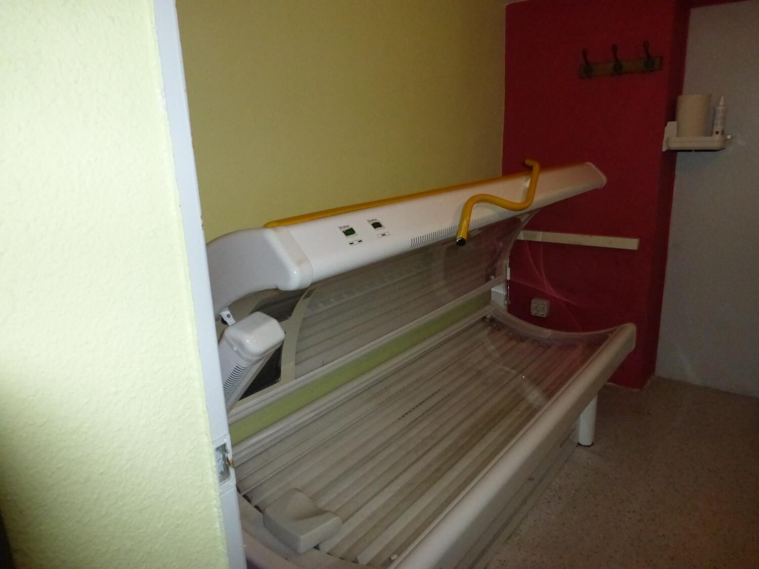 Un appareil de bronzage dans une pièce dont la porte est rouge et le mur, jaune.