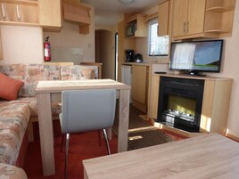 Interior compacto de uma RV com cozinha compacta, área de refeições e espaço para sentar.