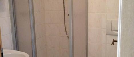 A bathroom with a glass-enclosed shower, a sink, and a toilet.