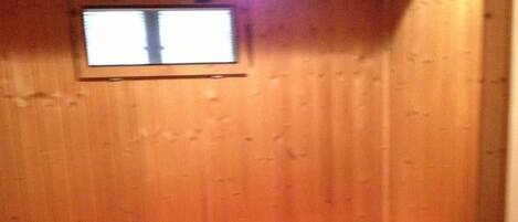 A wooden sauna with benches and a small window.