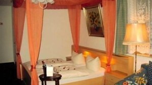 A hotel room with a bed, a bedside table, a lamp, and a curtain. - Gasthof Turm (Schoenwald)
