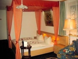 Quarto de hotel com cama, mesa de cabeceira, abajur e cortina.