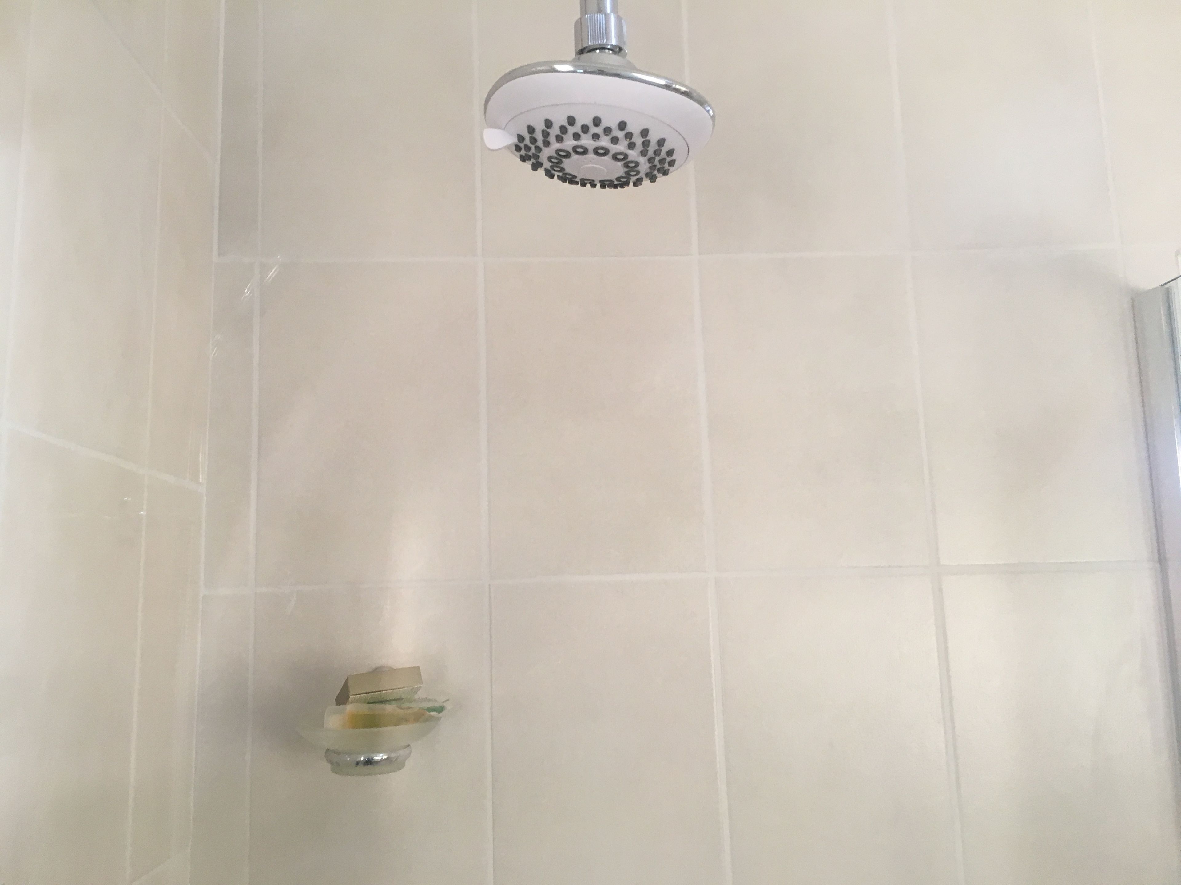 A showerhead in a bathroom with tiled walls.