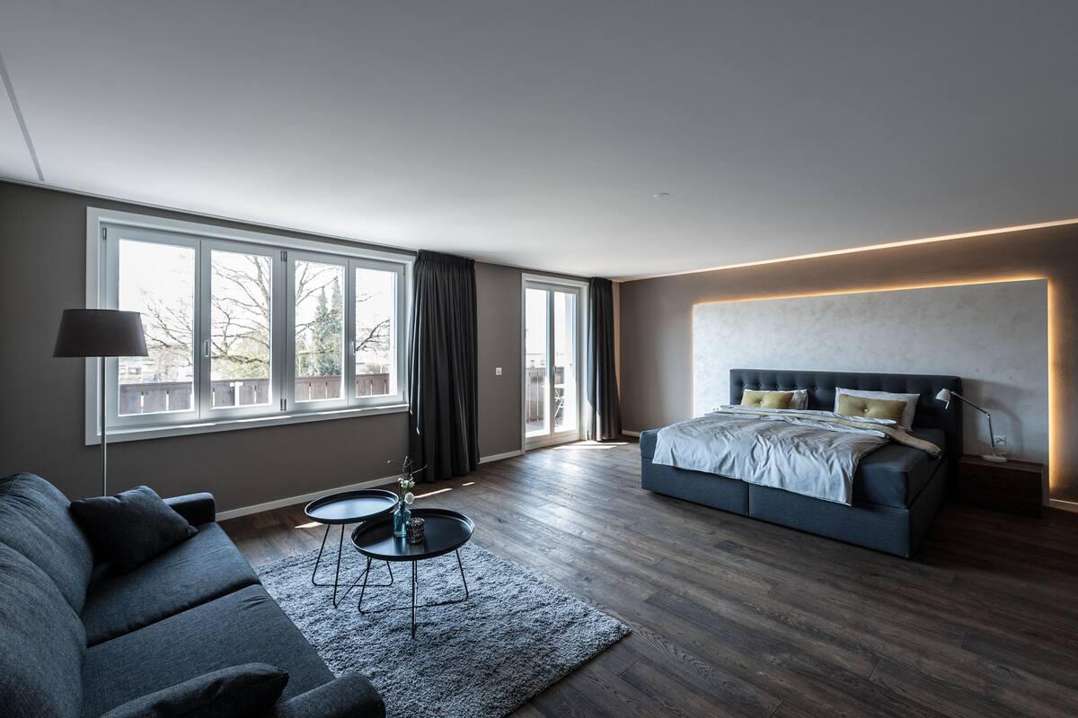 Ein modernes Schlafzimmer mit einem großen Bett, einer Couch und einem kleinen Tisch.