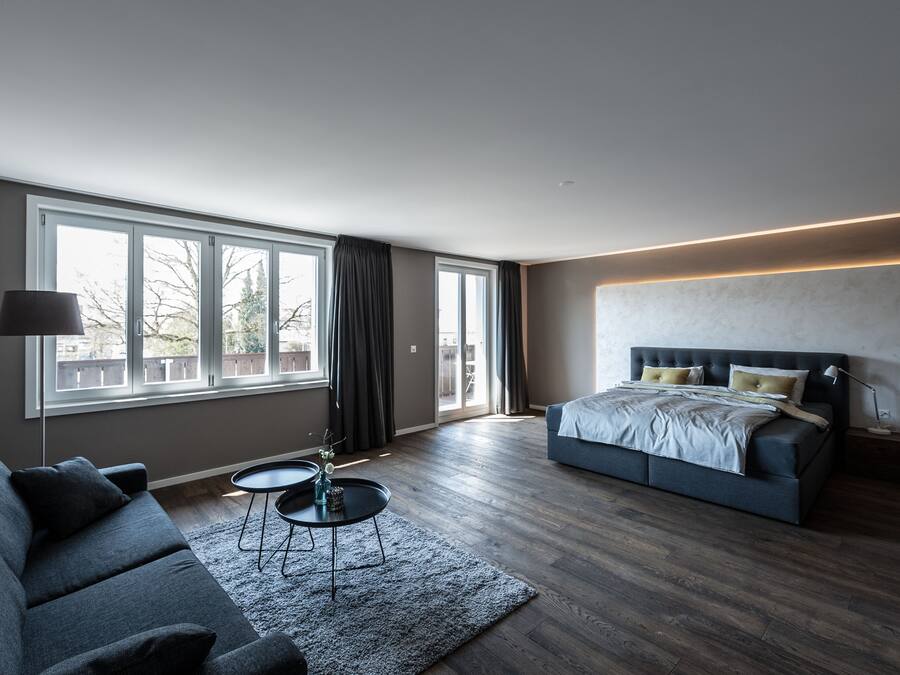 A modern bedroom with a large bed, a sofa, and a small table.