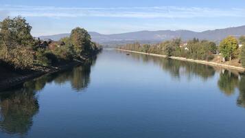 A calm river with a clear sky, surrounded by trees and distant mountains.