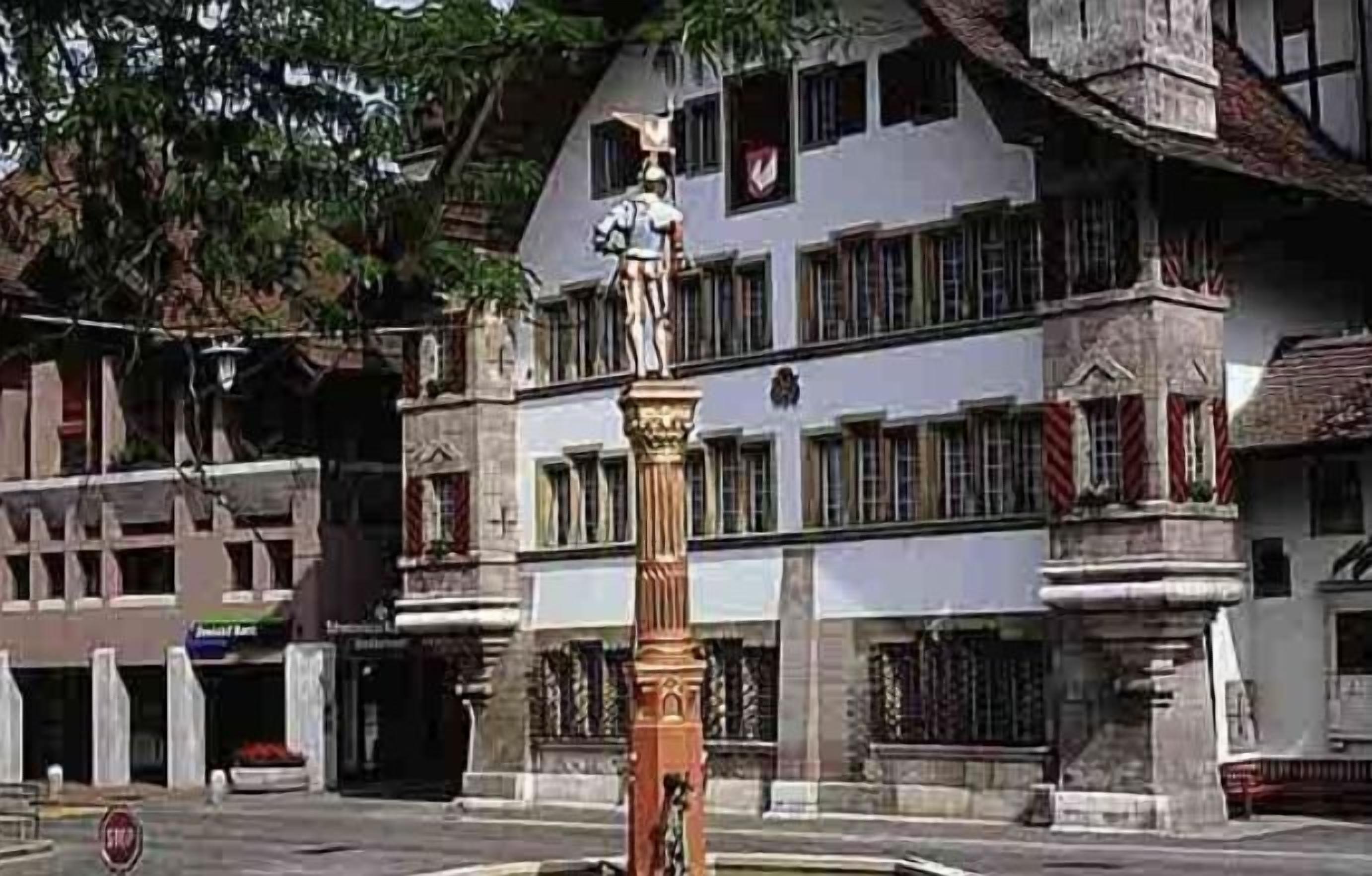 A building with a statue on a pedestal, multiple windows, and a stop sign.