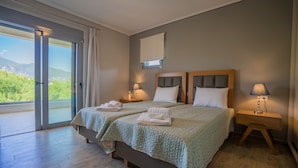 A double room with two beds, a balcony with a view, and a small bedside table with a lamp. - Zante Suites (Zakynthos)